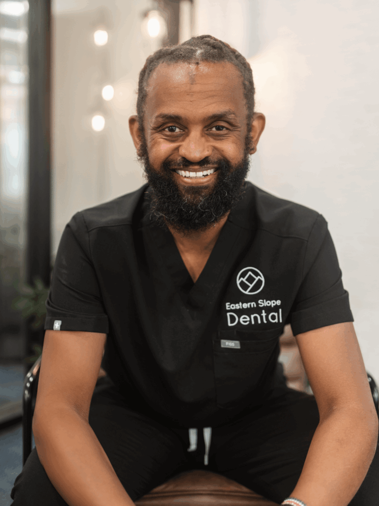 A seated dental professional in a black scrubs with "Eastern Slope Dental" logo, in a modern, well-lit setting.